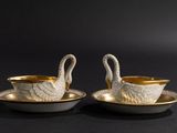 two white and gold swan shaped dishes on a black surface