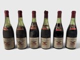 six bouteilles de vin sont alignées sur une surface blanche