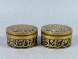 two black and gold boxes with designs on them on a white surface