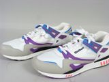 Des baskets violettes et blanches rehaussées de touches violettes reposent sur une surface blanche
