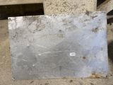 a piece of metal on the ground with a sticker on it