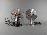 two metal fans sitting next to each other on a table