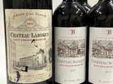 three bottles of red wine sitting next to each other on a table