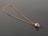 a close up of a gold necklace with a pearl on a black surface