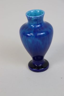 un vase en verre bleu posé sur une surface blanche