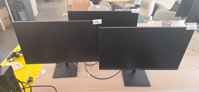 trois écrans d'ordinateur posés sur une table dans un magasin