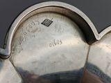 an antique silver plate with a heart shaped handle on a black background
