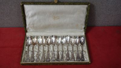 une boîte contenant des cuillères en argent, posée sur un fond rouge