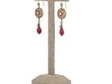 a pair of earrings on a stand with a white background