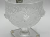 a clear glass vase with a small base on a white surface