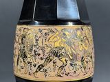 a black vase with a gold and black design on it