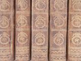several old books are lined up on a shelf in a library