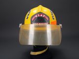 yellow fireman ' s helmet with clear vise on display against a black background