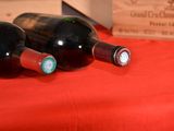 three bottles of wine sitting on a red table cloth