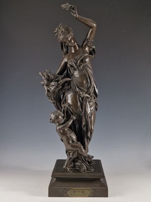 statue en bronze d'une femme tenant un oiseau sur un piédestal