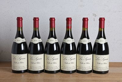 six bottles of red wine lined up on a wooden table