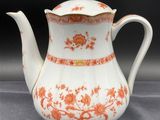 an orange and white tea pot with a lid on a table