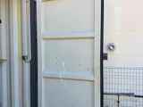 a white container sitting outside of a building with a door open