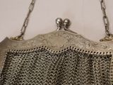 a silver purse hanging on a wall with a chain