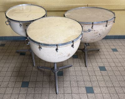 three drums sitting on a tiled floor in a room
