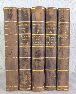 five old books are lined up in a row on a table