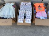 three cardboard boxes with clothes in them sitting on a sidewalk