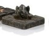 une petite statue de chien posée sur un bloc de pierre, à côté d'une autre statue de chien, plus petite, posée sur un bloc de pierre