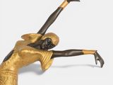 statue of a woman in a gold dress holding a tennis racquet