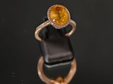 une bague sertie d'un saphir jaune et de diamants, posée sur un fond noir