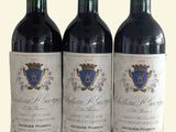three bottles of red wine sitting on top of a white table