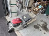 a lawn mower that is sitting outside of a garage