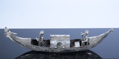 un bateau en argent avec trois personnes à bord, posé sur une table