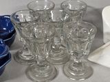 many glasses and bowls sitting on a counter top