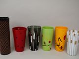 Plusieurs tasses de différentes couleurs sont alignées sur une surface blanche.