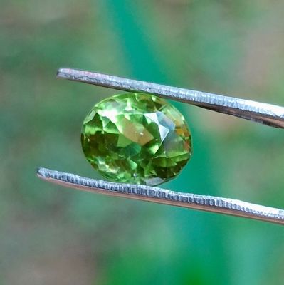 un gros plan sur une pierre précieuse verte tenue par un tweet