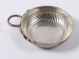 a small silver bowl with a handle on a white surface