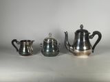 trois théières en argent et une cafetière sur une table