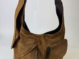 brown leather purse with zippers on top of it sitting on a white surface