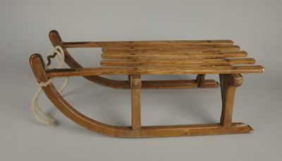 une vieille luge en bois posée sur une surface blanche