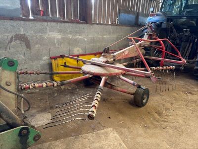 un tracteur garé à côté d'un autre tracteur équipé d'un râteau