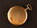an image of a gold pocket watch on a black surface