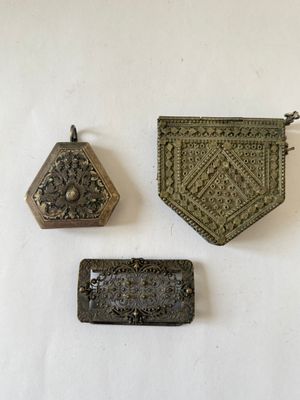 three pieces of metal are sitting on a white surface