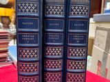 three blue books sitting on top of a red cloth covered table