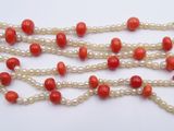 a close up of a necklace with red beads and white pearls