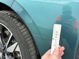 a person that is holding a remote control in front of a car