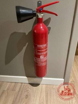 un extincteur rouge fixé au mur