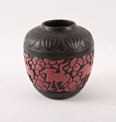 un vase noir et rouge posé sur une surface blanche