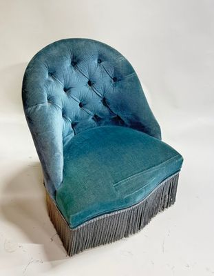 blue velvet chair with fringes and buttons on the back