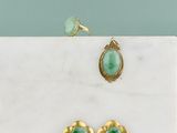 une paire de boucles d'oreilles en or et en jade et une bague posées sur une plaque de marbre