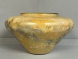 un grand vase jaune posé sur une surface blanche